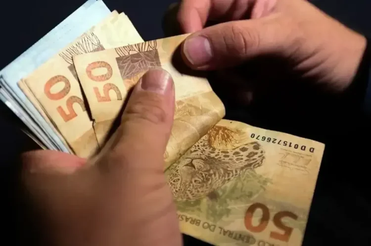 Pessoa contando cédulas de R$ 50, ilustrando o pagamento de valores por meio de PIX.