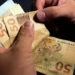 Pessoa contando cédulas de R$ 50, ilustrando o pagamento de valores por meio de PIX.