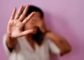 Mulher com a mão levantada em sinal de pare, simbolizando recusa à violência
