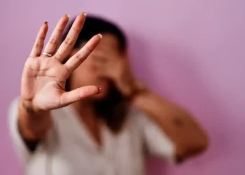 Mulher com a mão levantada em sinal de pare, simbolizando recusa à violência