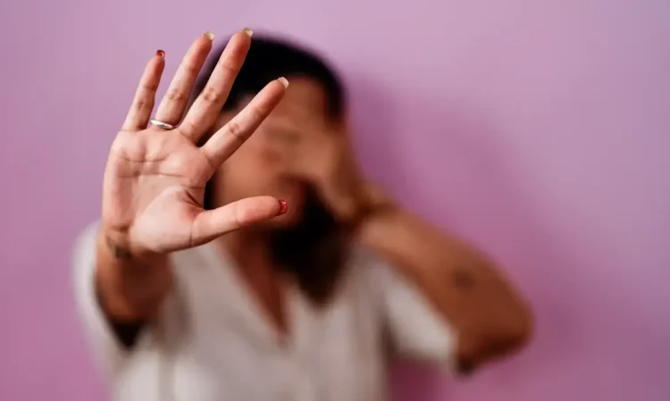 Mulher com a mão levantada em sinal de pare, simbolizando recusa à violência