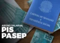 Carteira de trabalho e cédulas de dinheiro brasileiro sobre uma mesa, com texto sobre PIS/Pasep.