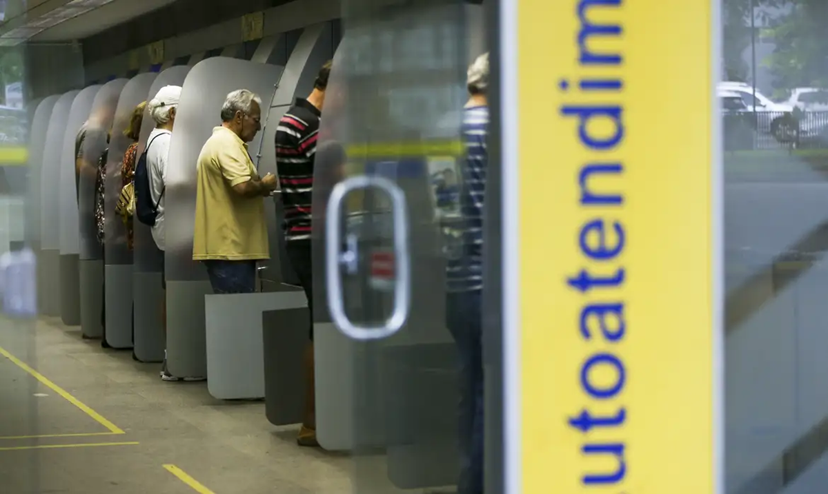 Pessoas utilizando terminais de autoatendimento em agência bancária