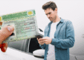 Homem conferindo celular com carteira de habilitação brasileira em destaque ao lado de carro branco
