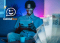 Homem sorridente usando tablet com o logo do Caixa Tem ao lado.