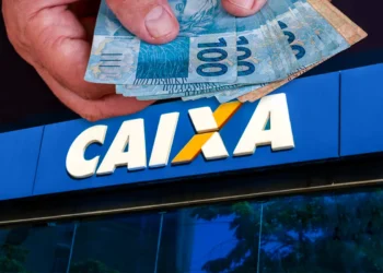 "Pessoa segurando dinheiro na frente de uma agência da Caixa Econômica Federal"
