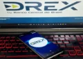 "Imagem de um celular exibindo o aplicativo DREX, com logo do Banco Central do Brasil ao fundo"