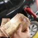 "Pessoa segurando cédulas de 50 reais enquanto abastece o carro, ilustrando os impactos das mudanças econômicas no cotidiano."