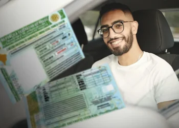 "Pessoa sorrindo dentro de um carro, segurando a Carteira Nacional de Habilitação (CNH)."