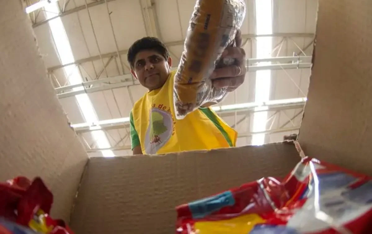 Homem colocando produtos da cesta básica em uma caixa, representando os impactos da isenção de impostos para reduzir custos para as famílias.