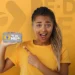 Jovem segurando celular com a logo do programa Pé-de-Meia do MEC em fundo amarelo.