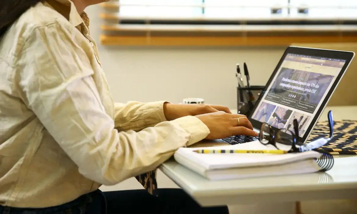 Pessoa acessando site institucional pelo notebook em ambiente de trabalho