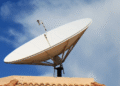 Antena parabólica digital instalada em telhado, com céu claro e nuvens.