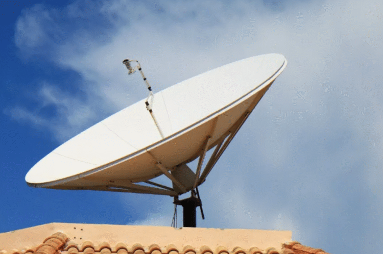 Antena parabólica digital instalada em telhado, com céu claro e nuvens.