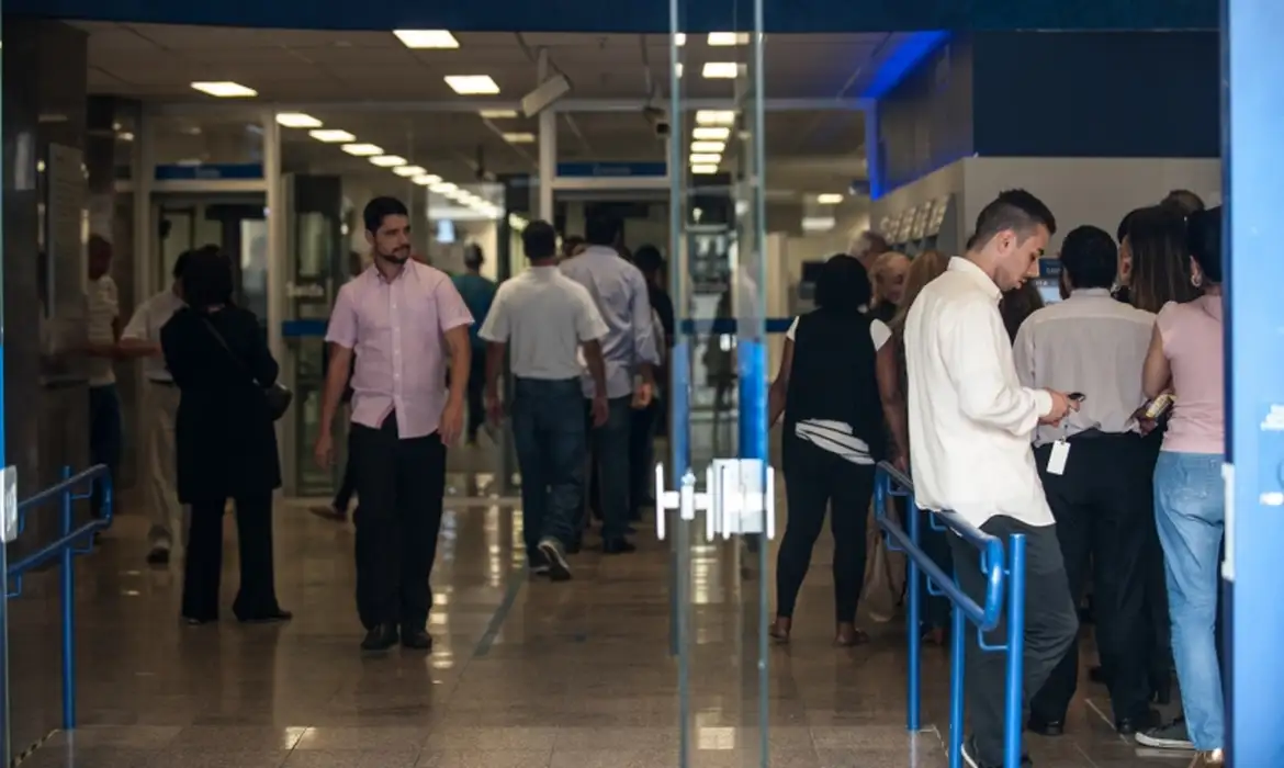 "Imagem de pessoas em uma agência bancária, sugerindo a importância de pesquisar antes de tomar decisões sobre troca de banco."