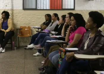 Mulheres atentas em aula de cursinho popular, recebendo bolsa de R$ 200 para ajudar nos estudos.