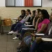 Mulheres atentas em aula de cursinho popular, recebendo bolsa de R$ 200 para ajudar nos estudos.