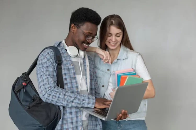 Estudantes com laptop e livros, em momento de interação