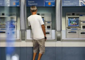 Pessoa utilizando um caixa eletrônico da Caixa Econômica Federal, simbolizando o processo de biometria para acesso à conta.