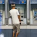 Pessoa utilizando um caixa eletrônico da Caixa Econômica Federal, simbolizando o processo de biometria para acesso à conta.