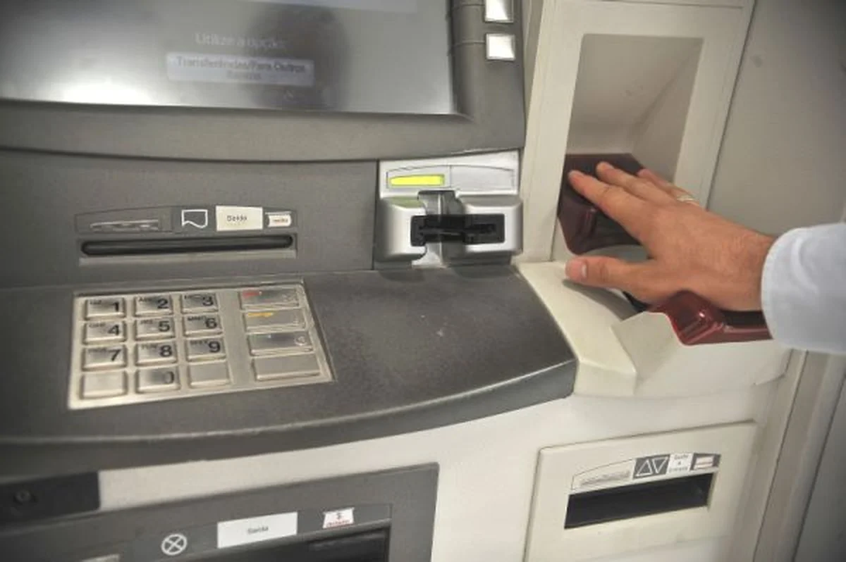 Pessoa realizando a biometria no caixa eletrônico da Caixa Econômica Federal, colocando a impressão digital.