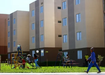 Crianças brincando em área comum de conjunto habitacional popular