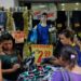 Clientes em frente a loja popular com promoções e roupas expostas