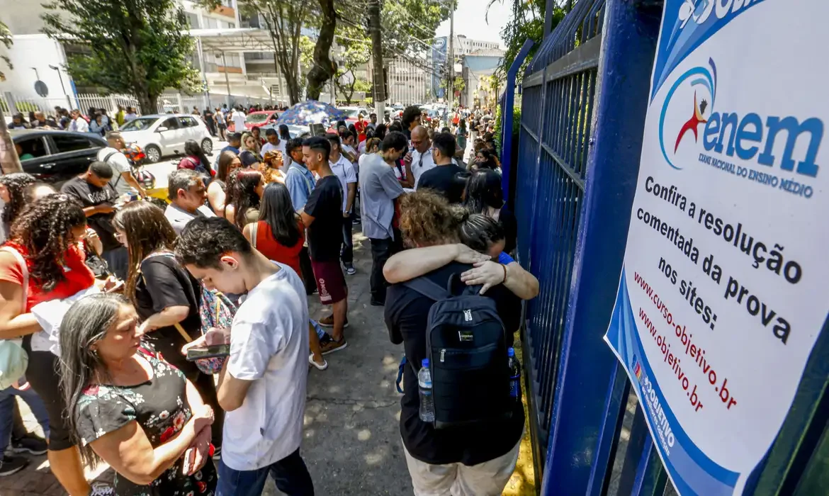 Grupo de pessoas aguardando do lado de fora de uma escola para realizar a prova do Enem.