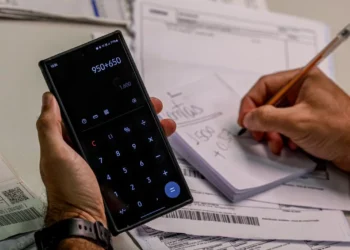 Pessoa utilizando calculadora e fazendo anotações enquanto calcula dívidas, simbolizando o esforço para negociar com o Serasa.
