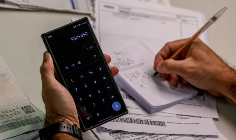 Pessoa utilizando calculadora e fazendo anotações enquanto calcula dívidas, simbolizando o esforço para negociar com o Serasa.