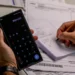 Pessoa utilizando calculadora e fazendo anotações enquanto calcula dívidas, simbolizando o esforço para negociar com o Serasa.