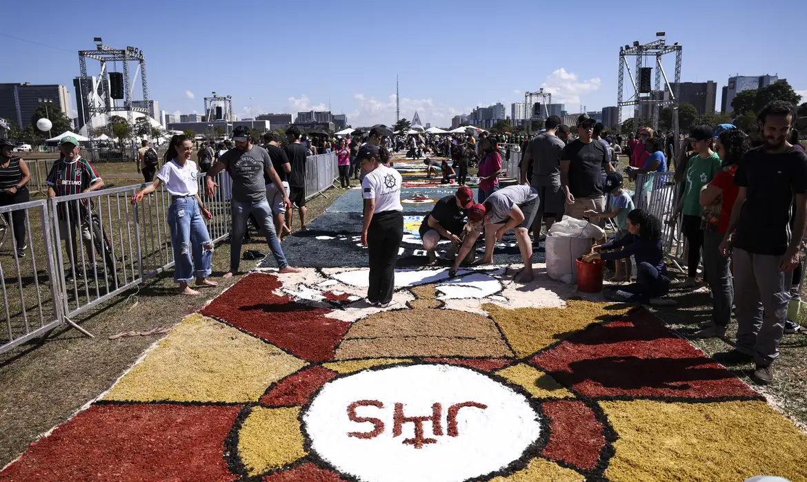 "Pessoas participando da confecção do tapete de Corpus Christi, tradição religiosa do Brasil"