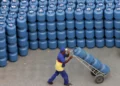 Trabalhador transportando botijões de gás empilhados