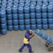 Trabalhador transportando botijões de gás empilhados