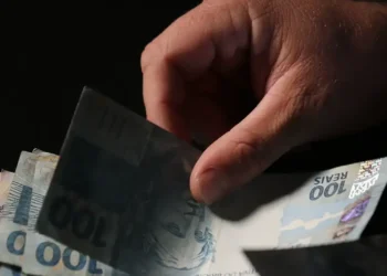 Pessoa segurando cédulas de R$ 100 e R$ 50, ilustrando a oportunidade de crédito para trabalhadores