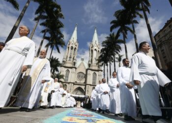 "Celebração de Corpus Christi no Brasil com padres desfilando em frente a uma catedral"