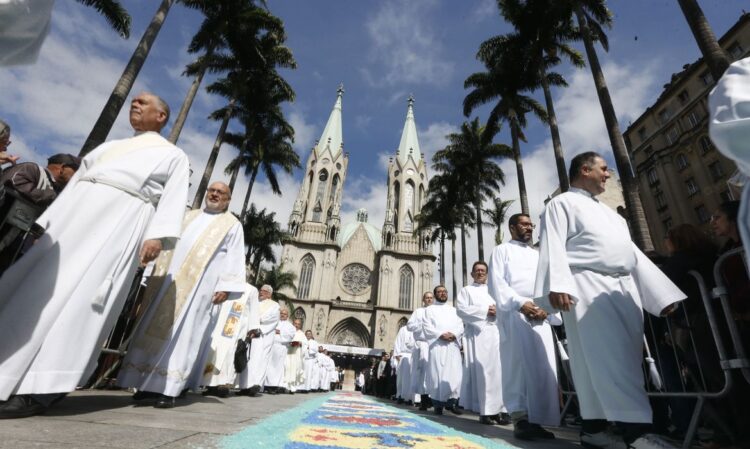 "Celebração de Corpus Christi no Brasil com padres desfilando em frente a uma catedral"