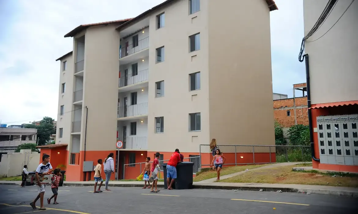 Crianças e moradores circulando em área externa de conjunto habitacional