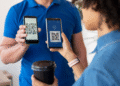 Dois smartphones exibindo QR codes, com uma pessoa segurando um café e outra escaneando o código, sugerindo o uso de IA para detectar fraudes em pagamentos.