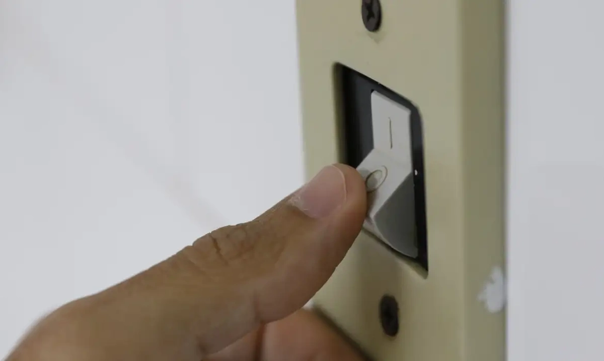 Pessoa desligando um interruptor de luz na parede