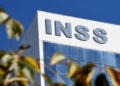 Imagem da fachada do prédio do INSS, destacando o nome da instituição, com um céu azul claro ao fundo. A imagem é relevante para o anúncio de serviços do INSS durante o feriado de Corpus Christi.