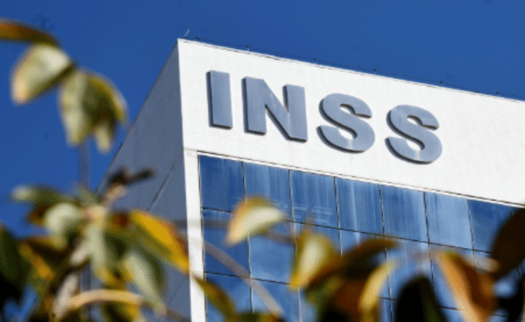 Imagem da fachada do prédio do INSS, destacando o nome da instituição, com um céu azul claro ao fundo. A imagem é relevante para o anúncio de serviços do INSS durante o feriado de Corpus Christi.
