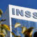 Imagem da fachada do prédio do INSS, destacando o nome da instituição, com um céu azul claro ao fundo. A imagem é relevante para o anúncio de serviços do INSS durante o feriado de Corpus Christi.