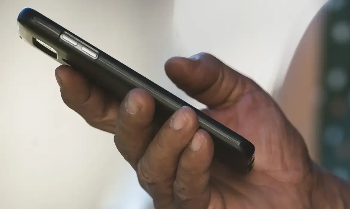 Mão segurando um celular para leitura de mensagens.