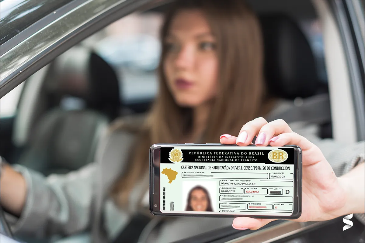 Mulher dentro do carro exibindo a CNH digital no celular.