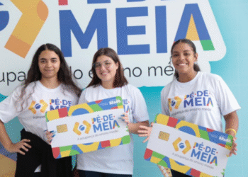 Três jovens sorrindo e segurando cartões do programa Pé de Meia, com a inscrição A poupança do ensino médio.
