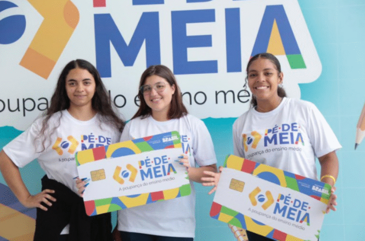 Três jovens sorrindo e segurando cartões do programa Pé de Meia, com a inscrição A poupança do ensino médio.