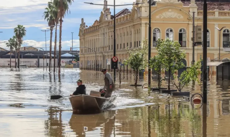 Barco transporta pessoas em rua alagada após enchente em área urbana