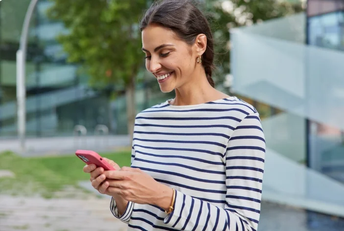 Mulher consultando comprovante bancário pelo celular, representando a redução do uso de papel.