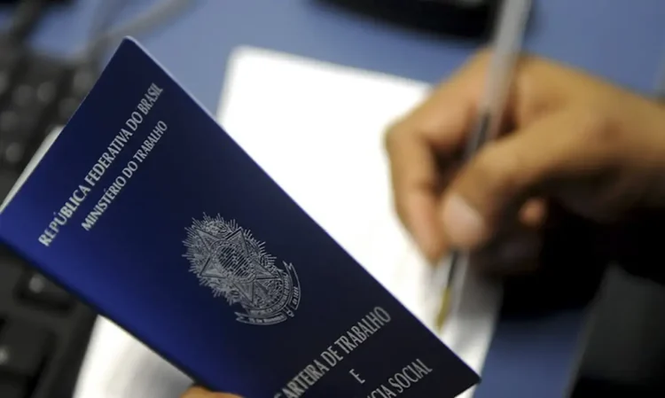 "Carteira de trabalho sendo preenchida, simbolizando a relação entre empregador e trabalhador"